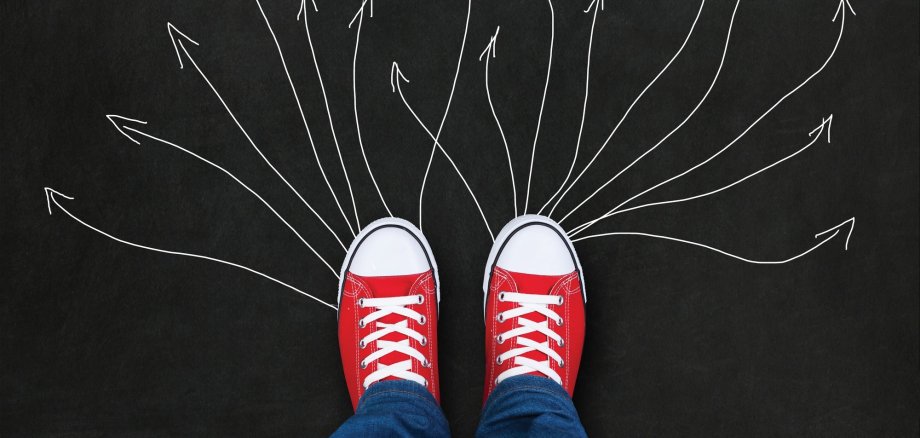 Feet wearing red shoes on black background with arrows. choice concept