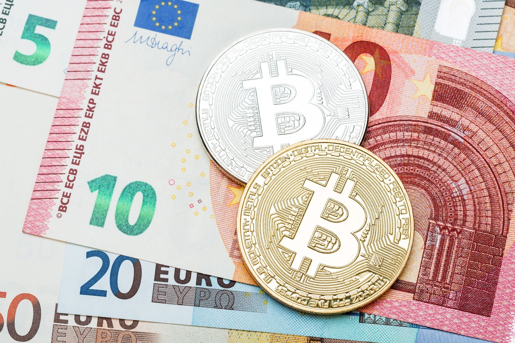 Silver and golden Bitcoin close-up. Euro currency as a backgroun