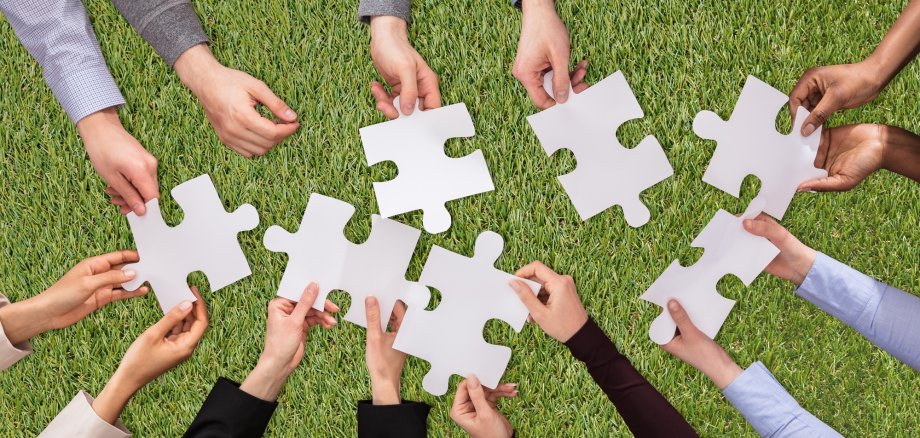 People Hands Joining The White Jigsaw Puzzles On Turf