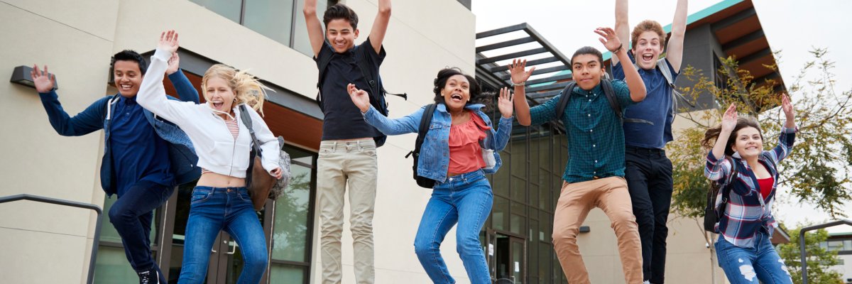 Group Of High School Students Jumping In Air Outside College Buildings Group Of High School Students Jumping In Air Outside College Buildings