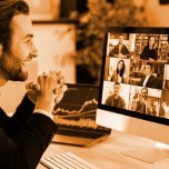 Successful positive Caucasian business man in a suit, sits at a workplace in the office, negotiating with partners on a video conference using a computer, discussing new project, terms of cooperation